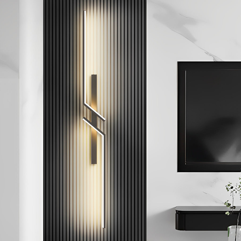 Modern geometric wall sconce with a gold and black finish, mounted on a white wall.