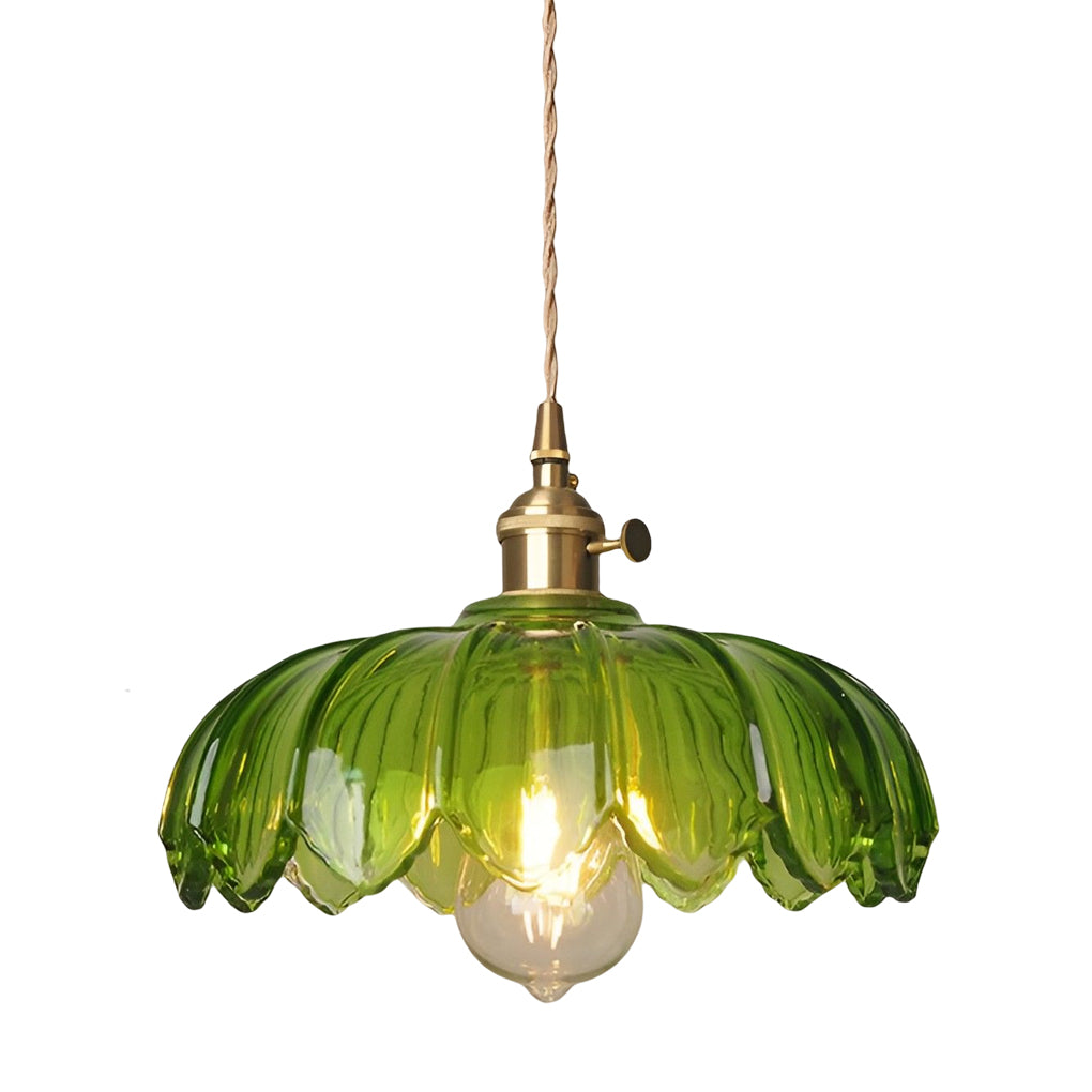 Green glass pendant light isolated on white background with decorative scalloped shade and warm glow.