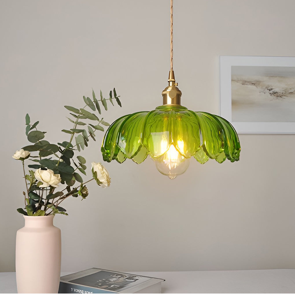 Green glass pendant light with ribbed scalloped design and brass details, adding color and warmth to the space.