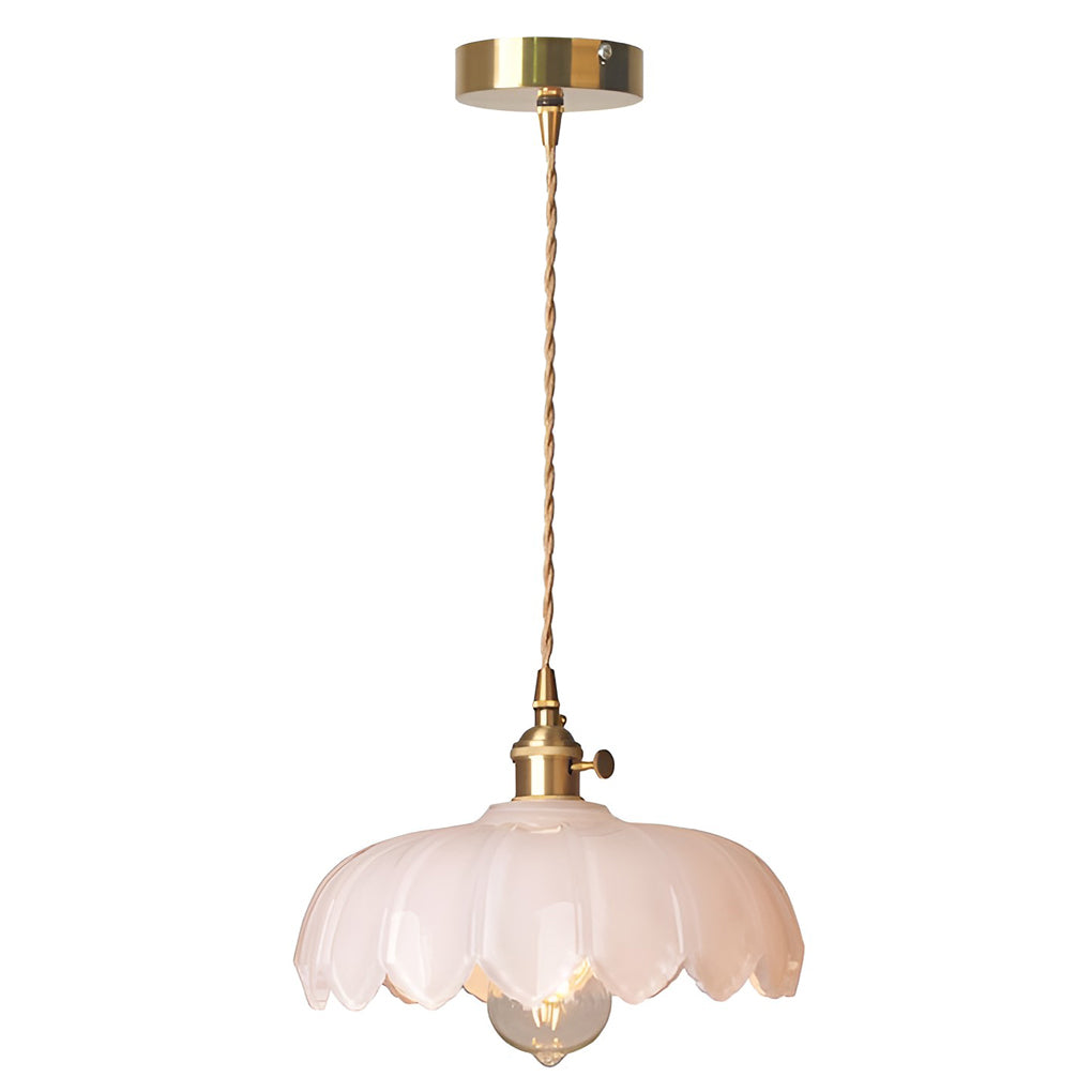 Pink glass pendant light hanging from ceiling, compact scalloped design with brass accents and warm lighting.