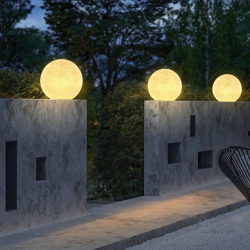 Globe pillar lights placed on concrete walls near an entryway