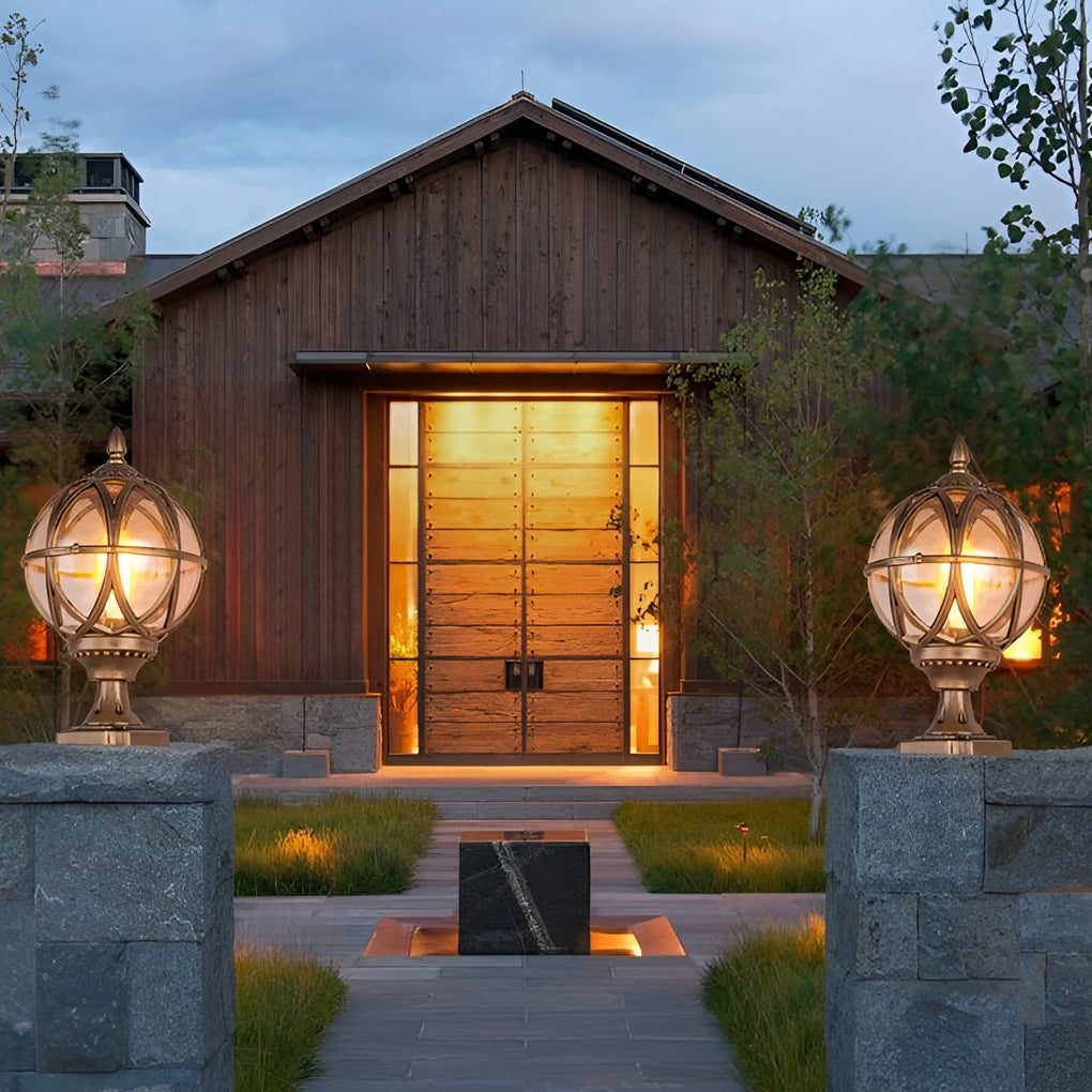 Globe pillar lights with decorative bronze frame mounted on stone pillar at entrance.
