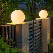 Globe pillar lights installed on outdoor fence posts at night