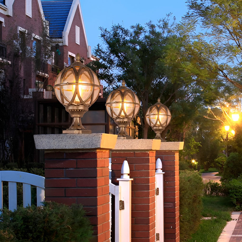 Globe pillar lights with ornate bronze frame, installed on brick pillars in front yard.