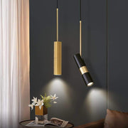 Two adjustable cylindrical pendant lights in gold and black above a modern living room's table.