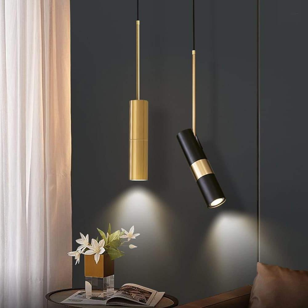 Two adjustable cylindrical pendant lights in gold and black above a modern living room's table.