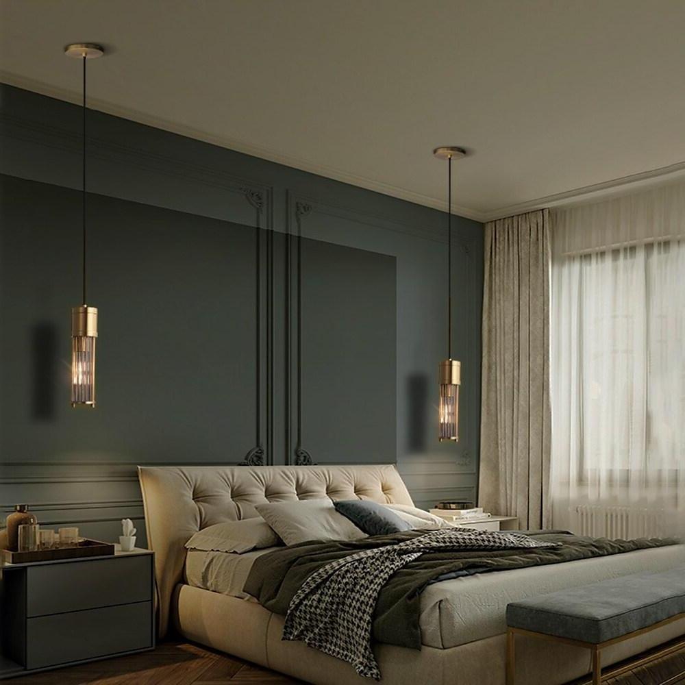 Gold cylinder pendant light creating ambient lighting in master bedroom.