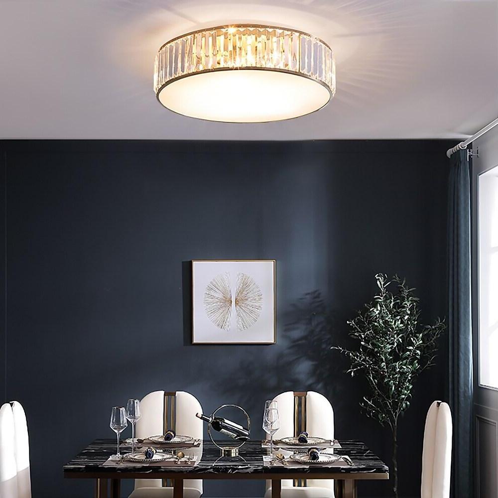 Gold drum ceiling light installed in a stylish dining space with dark accent walls.