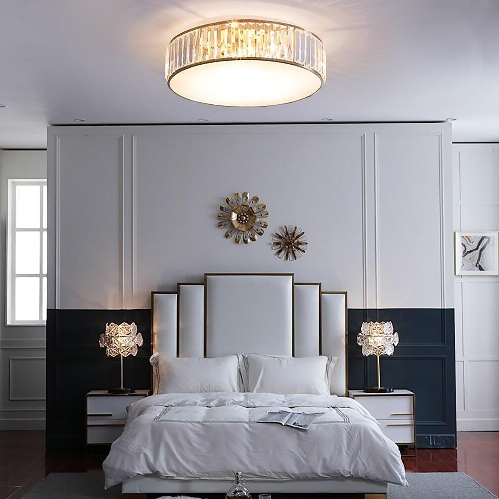 Gold drum ceiling light mounted in a contemporary bedroom with elegant wall decor.