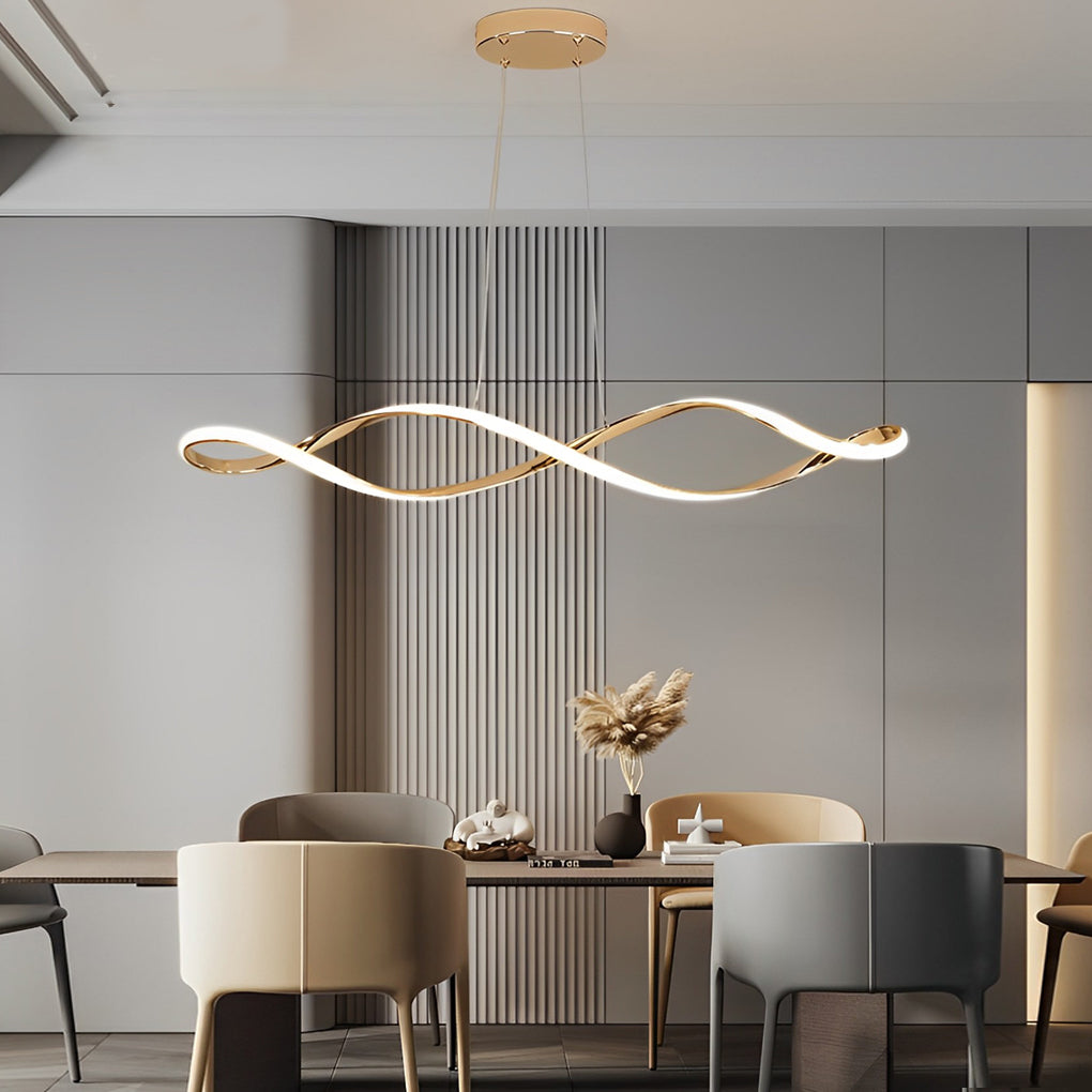 Waveform pendant light in gold finish hanging above dining table with decorative plants.