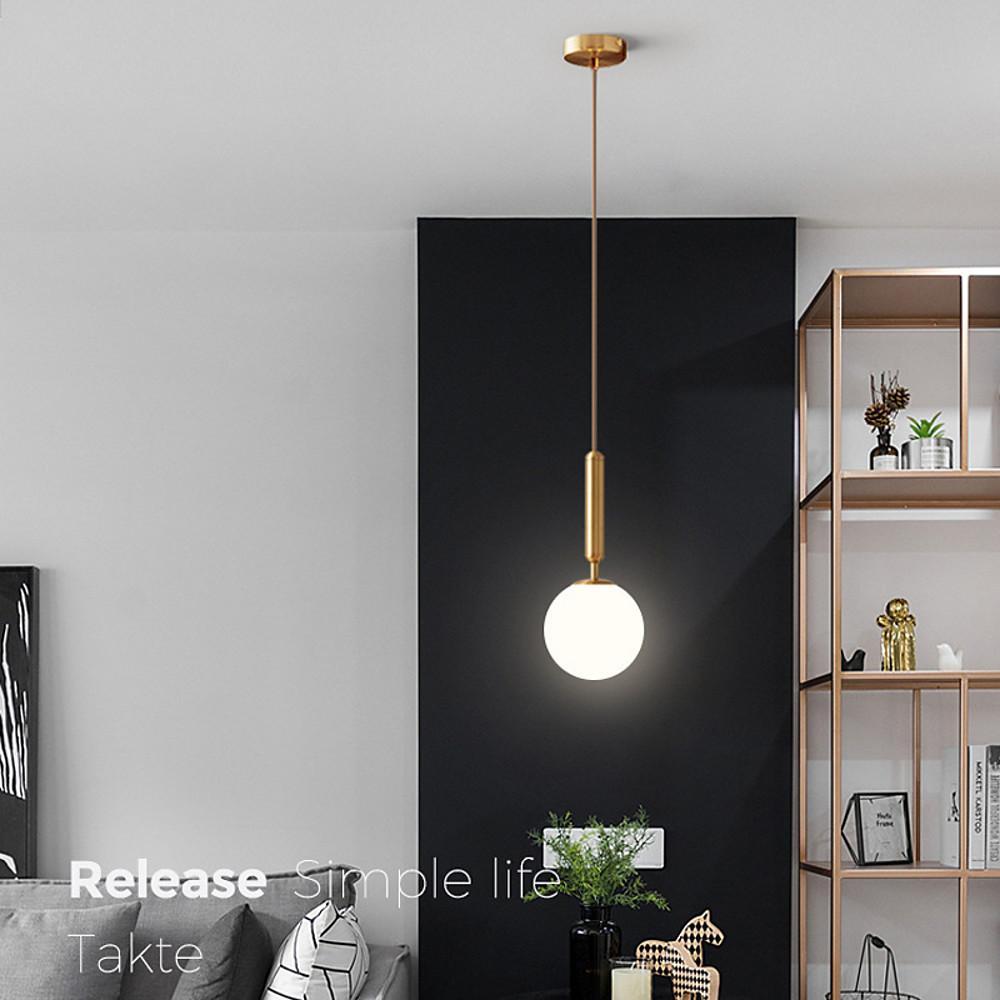 Single gold hanging lights fixture against a black accent wall in a modern stylish living room.