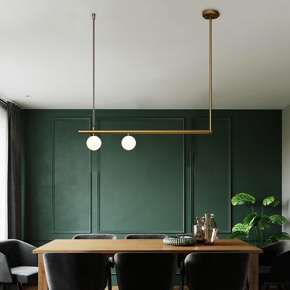 Gold linear pendant light over dining table in green accent interior.