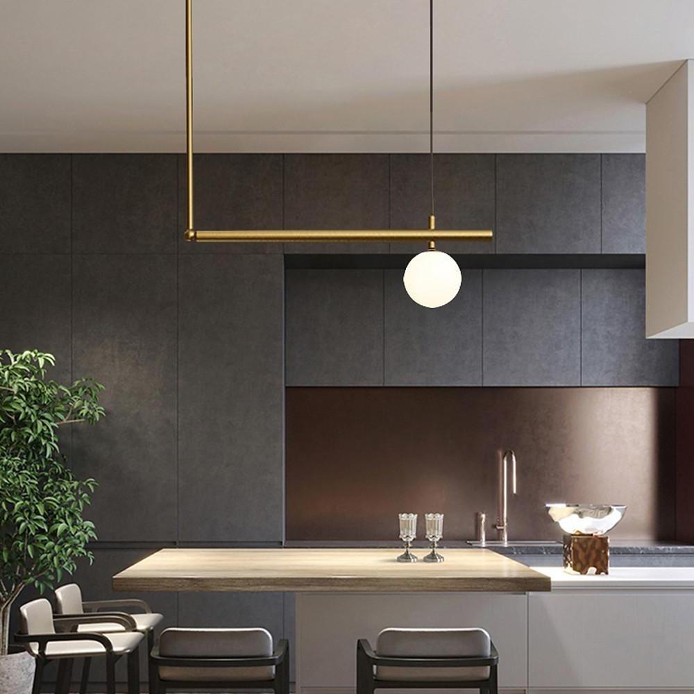 Minimalist gold linear pendant light in contemporary kitchen interior.