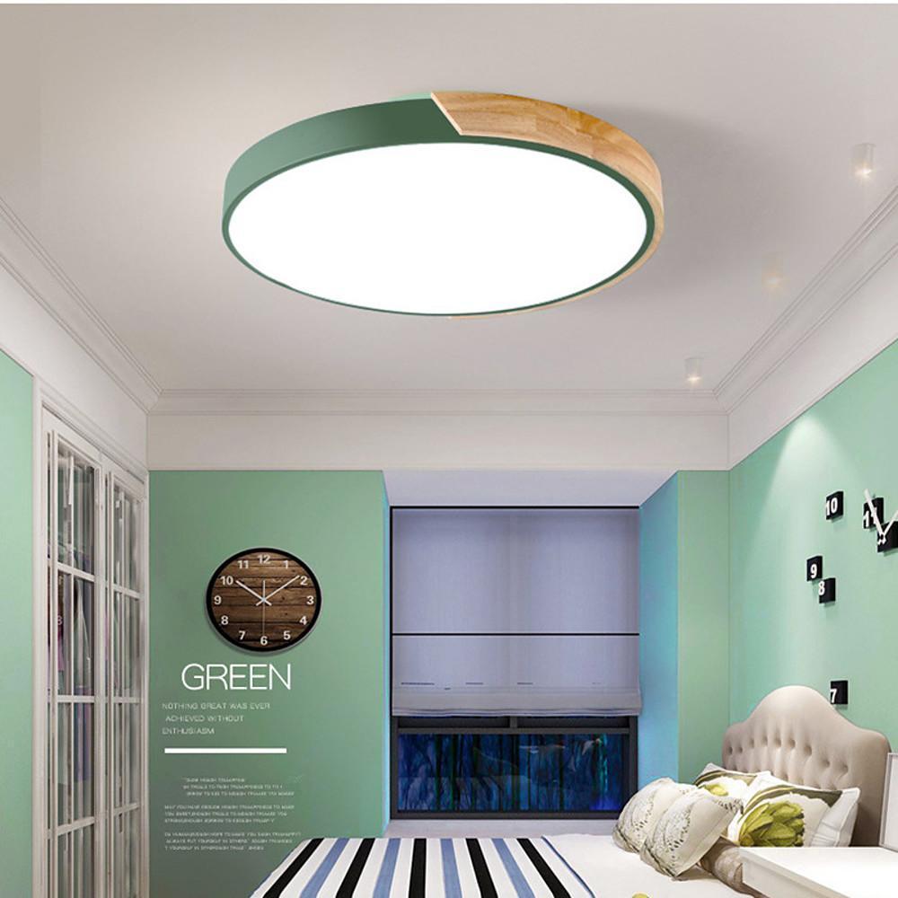 Green nordic wooden ceiling light glowing brightly in a modern bedroom with green walls here.