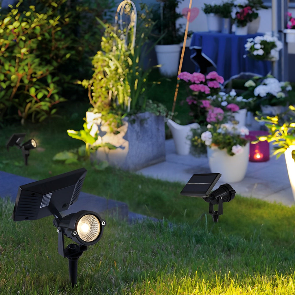 Ground spike solar lights placed in a garden lawn, highlighting plants and flower pots with warm focused light.