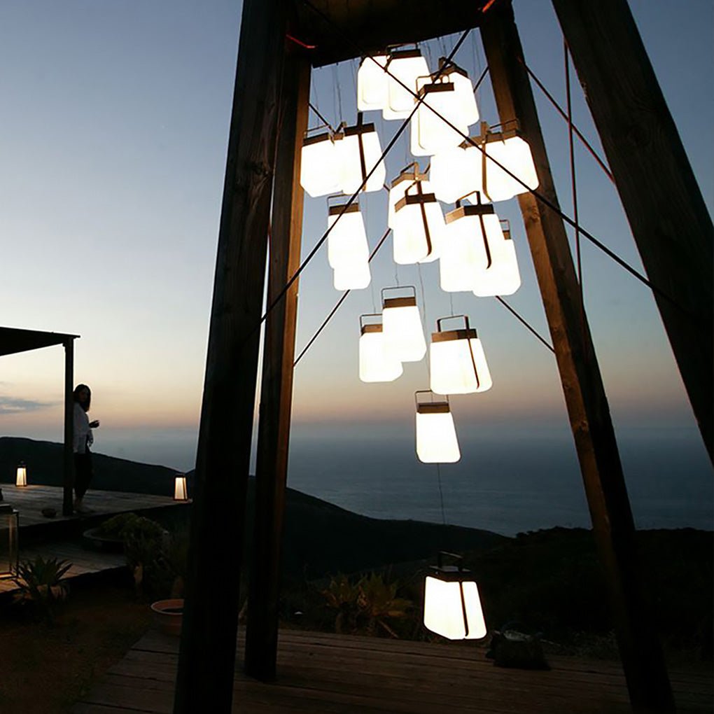 Hanging solar lantern lights suspended from a wooden structure, creating a cozy decorative glow at sunset.