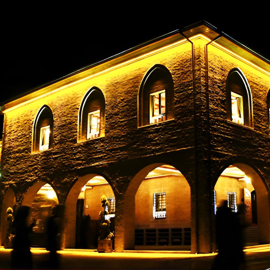 Historic stone building highlighted with warm facade wall washer lights at night.