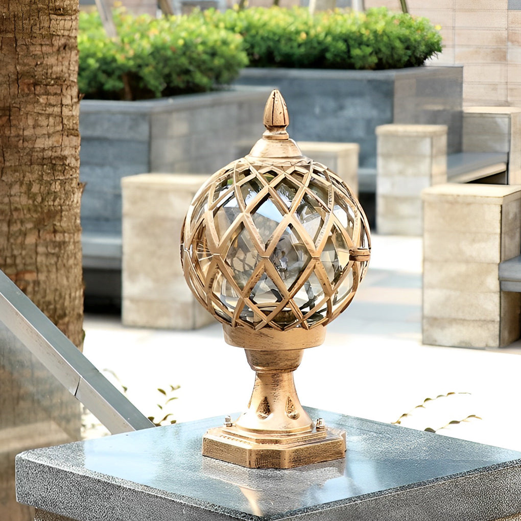 Three home pillar lights with gold lattice spheres, lined up on white pillars in a landscaped outdoor area.
