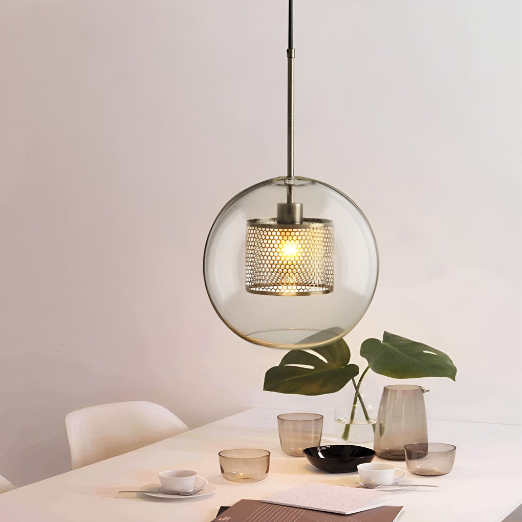 Large Clear Glass Globe Pendant with a brass mesh core above a minimalist white dining table.