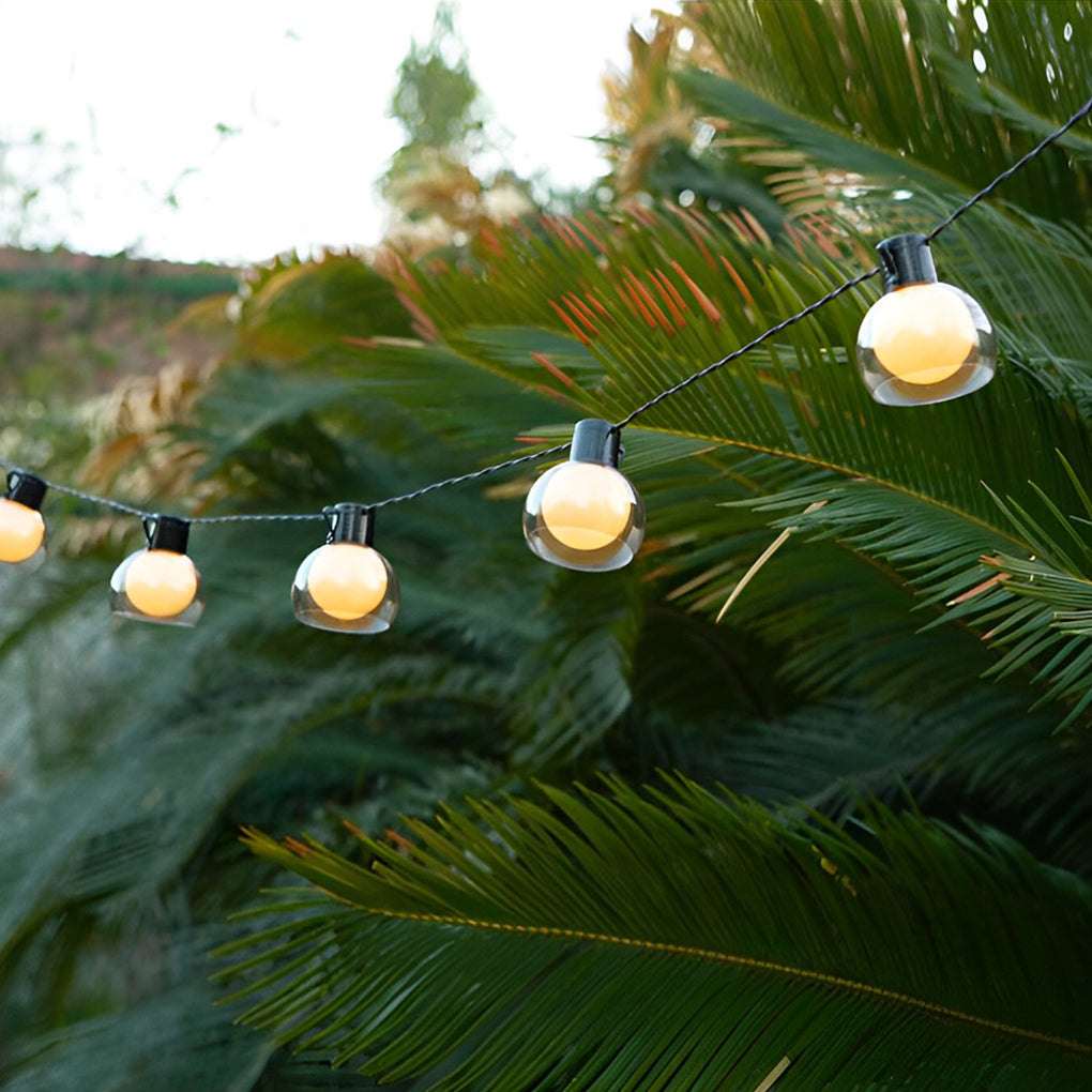 LED globe string lights suspended between structures, forming decorative outdoor lighting with softly glowing bulbs.