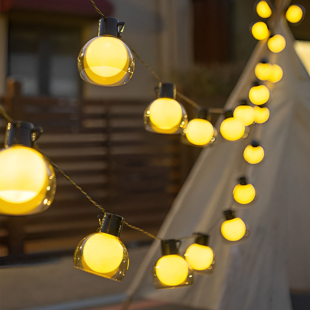 LED globe string lights hung along a modern building exterior, adding festive ambiance to an outdoor courtyard.
