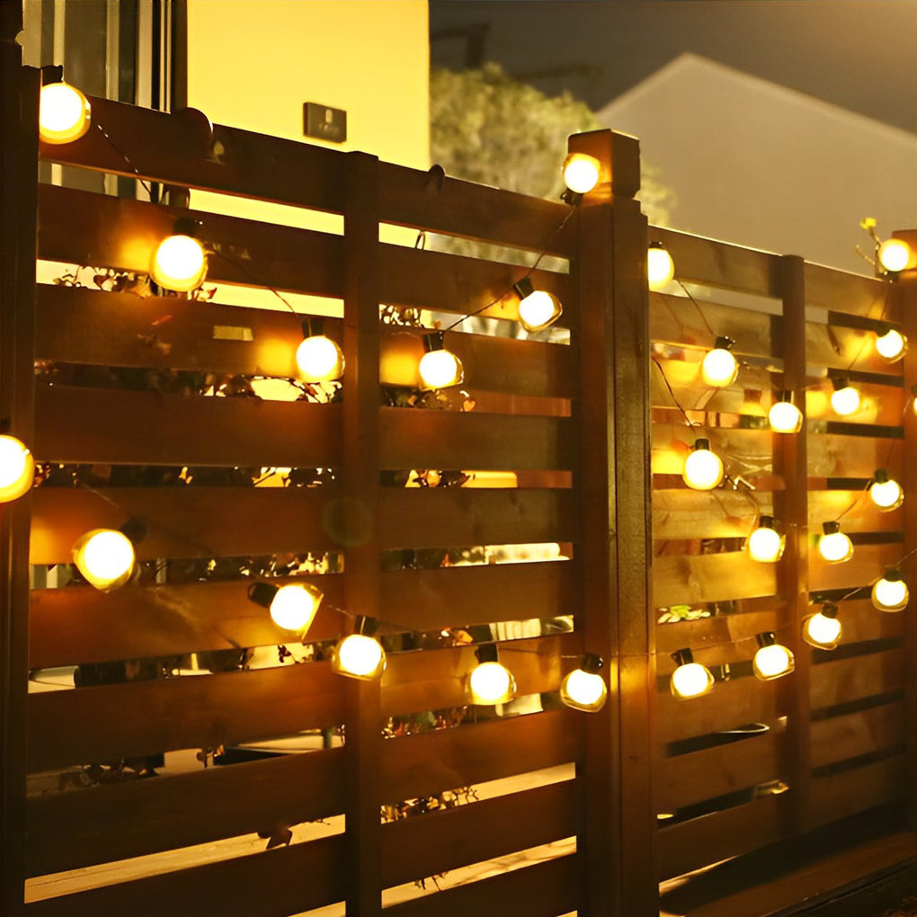 LED globe string lights mounted across a wooden fence, creating a cozy and festive outdoor boundary lighting effect.