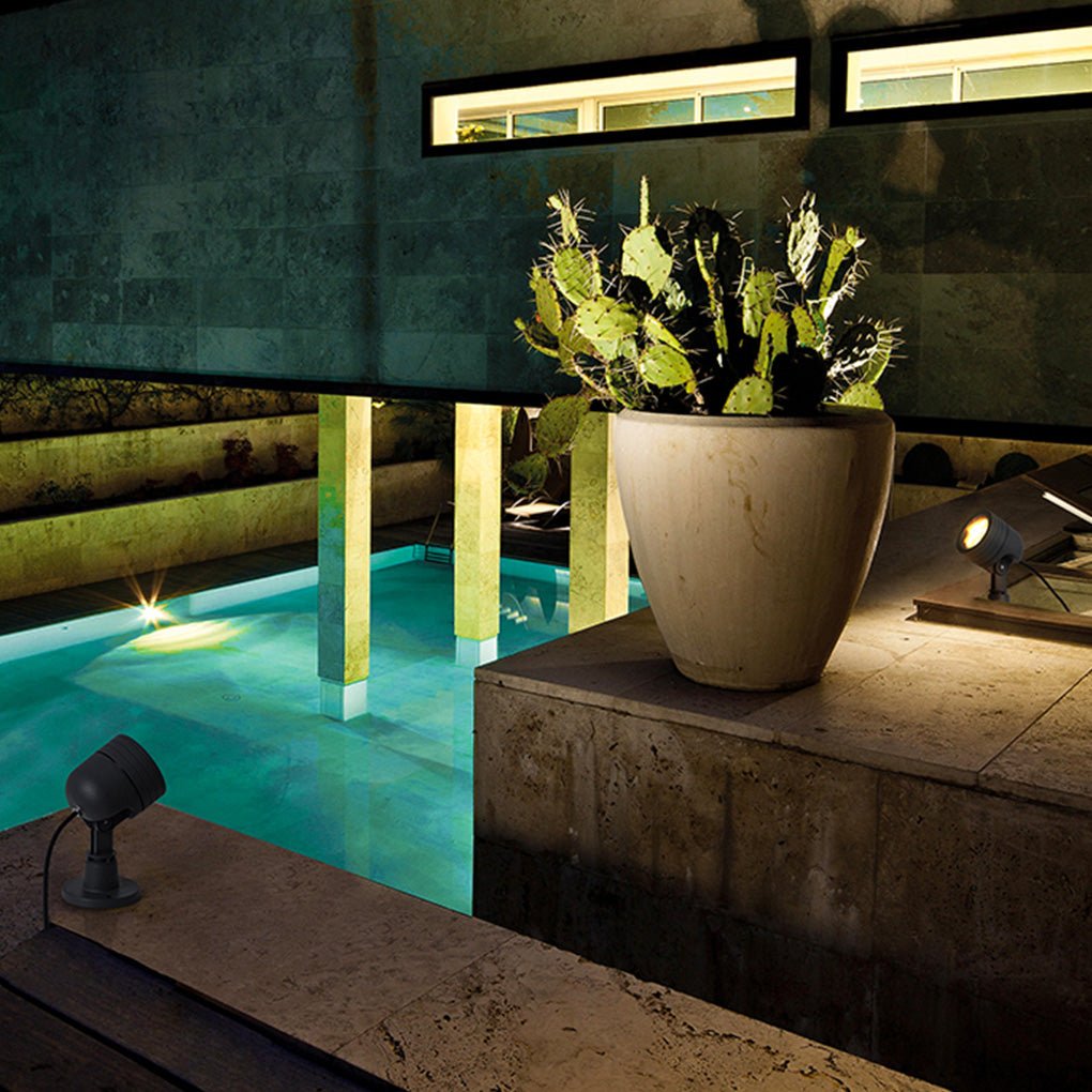 LED landscape spot lights illuminating a poolside planter, adding ambient lighting to a modern outdoor living space.