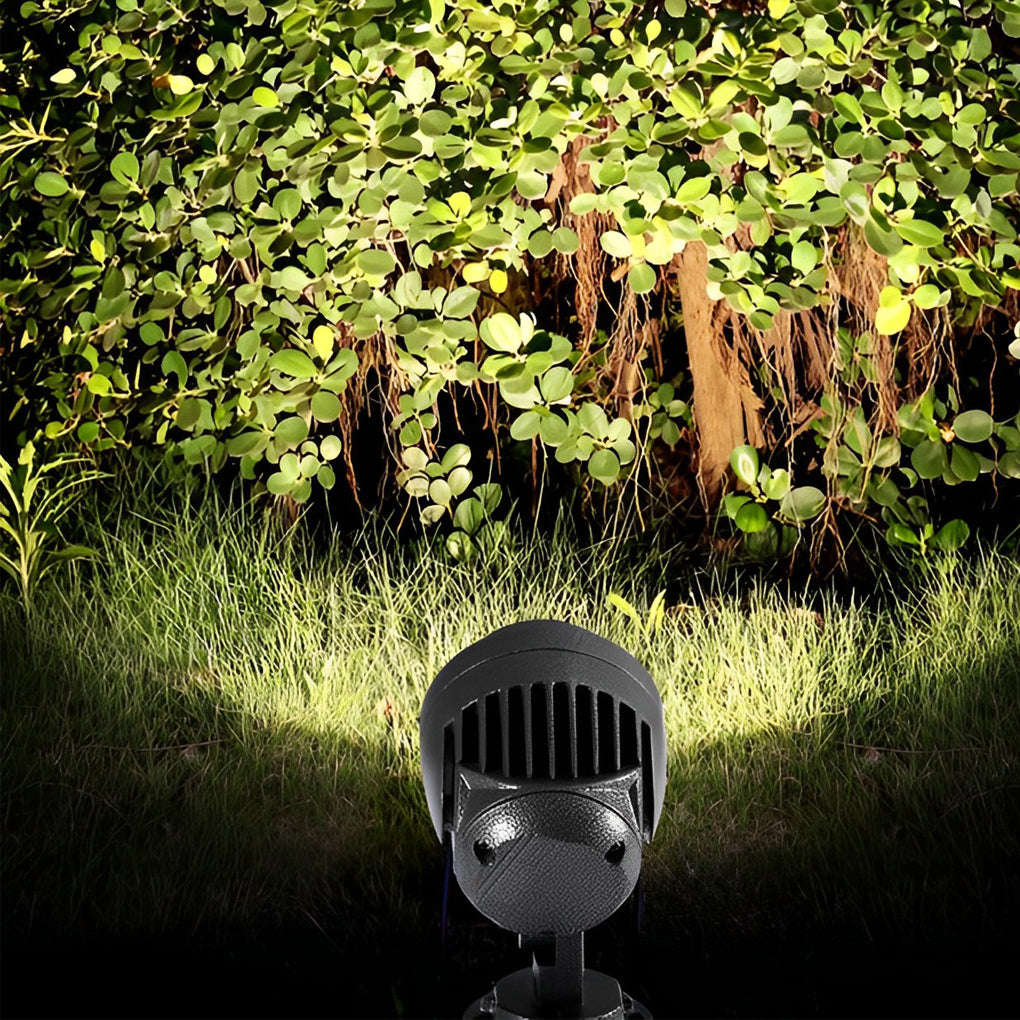 LED landscape spotlight washing light across dense bushes and greenery at night.