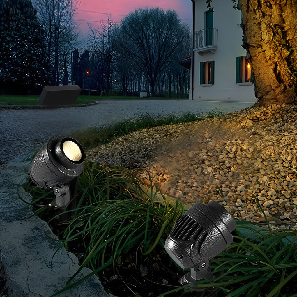 LED landscape spotlight installed along a gravel path beside ornamental plants.