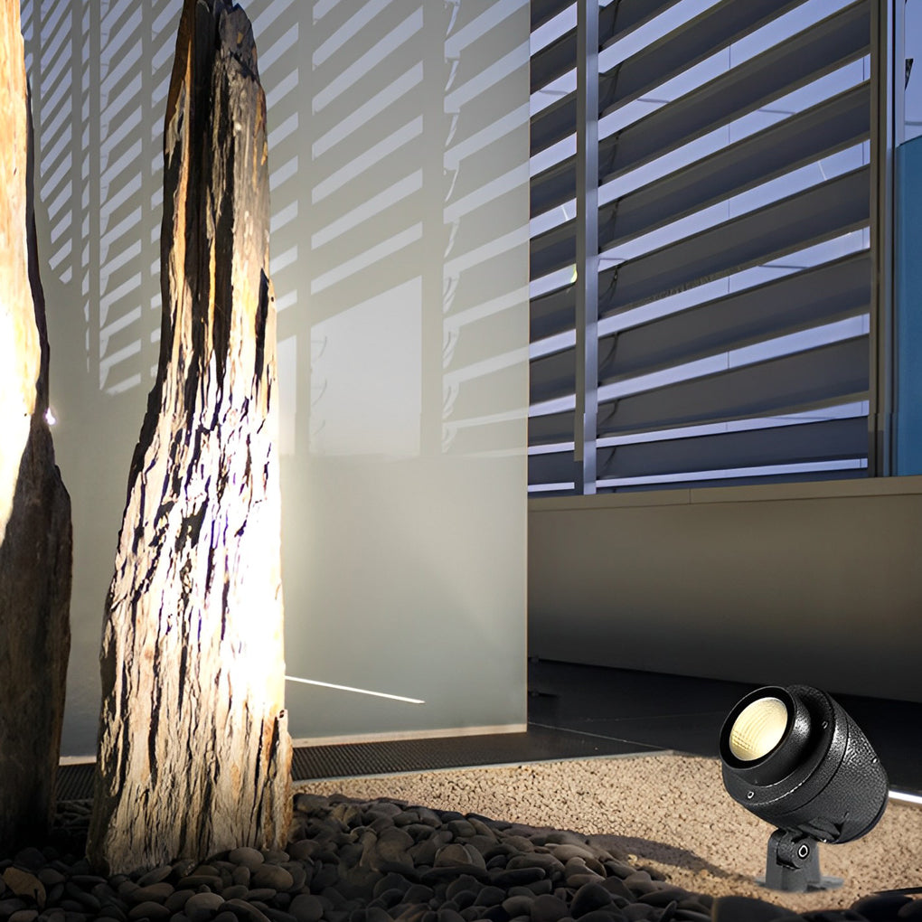 LED landscape spotlight casting dramatic light patterns on a tree near a fence.