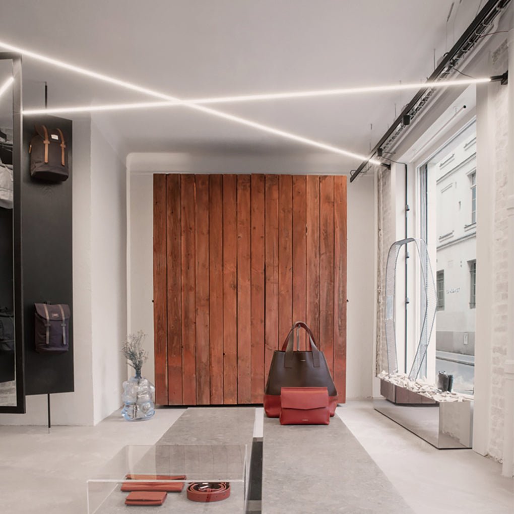 Long linear led lights strips for room crisscrossing the high ceiling of a modern retail space.