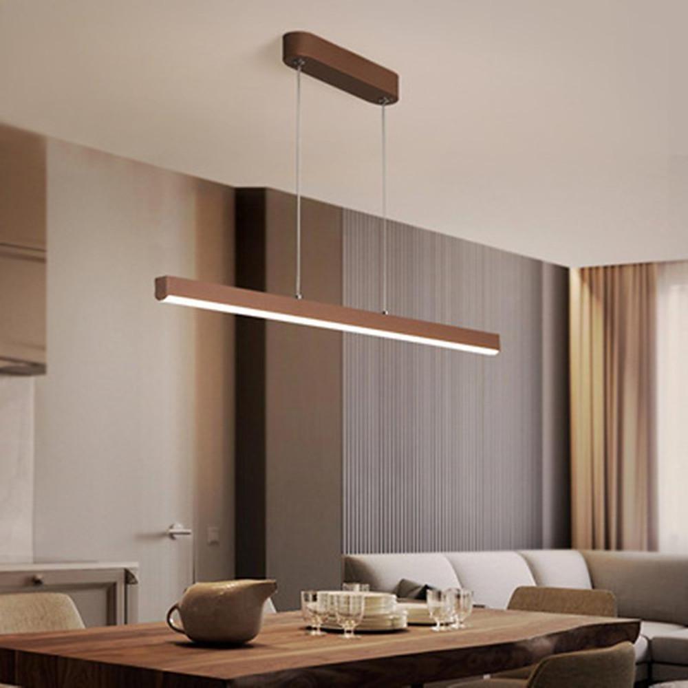 Linear pendant light fixture hanging above dining table in modern interior.