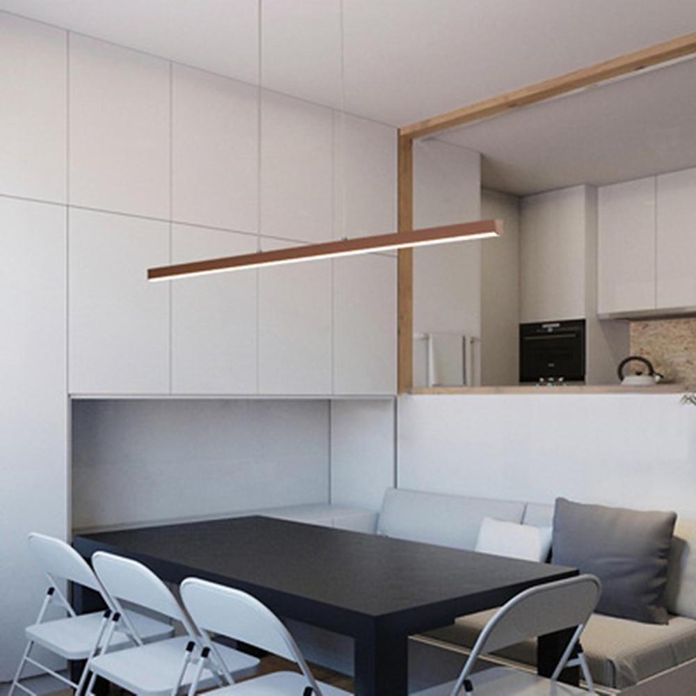 Linear pendant light fixture over compact dining area in modern apartment.