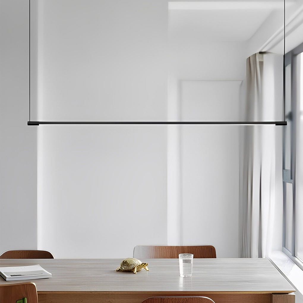 Linear pendant light fixture suspended above wooden table near window.