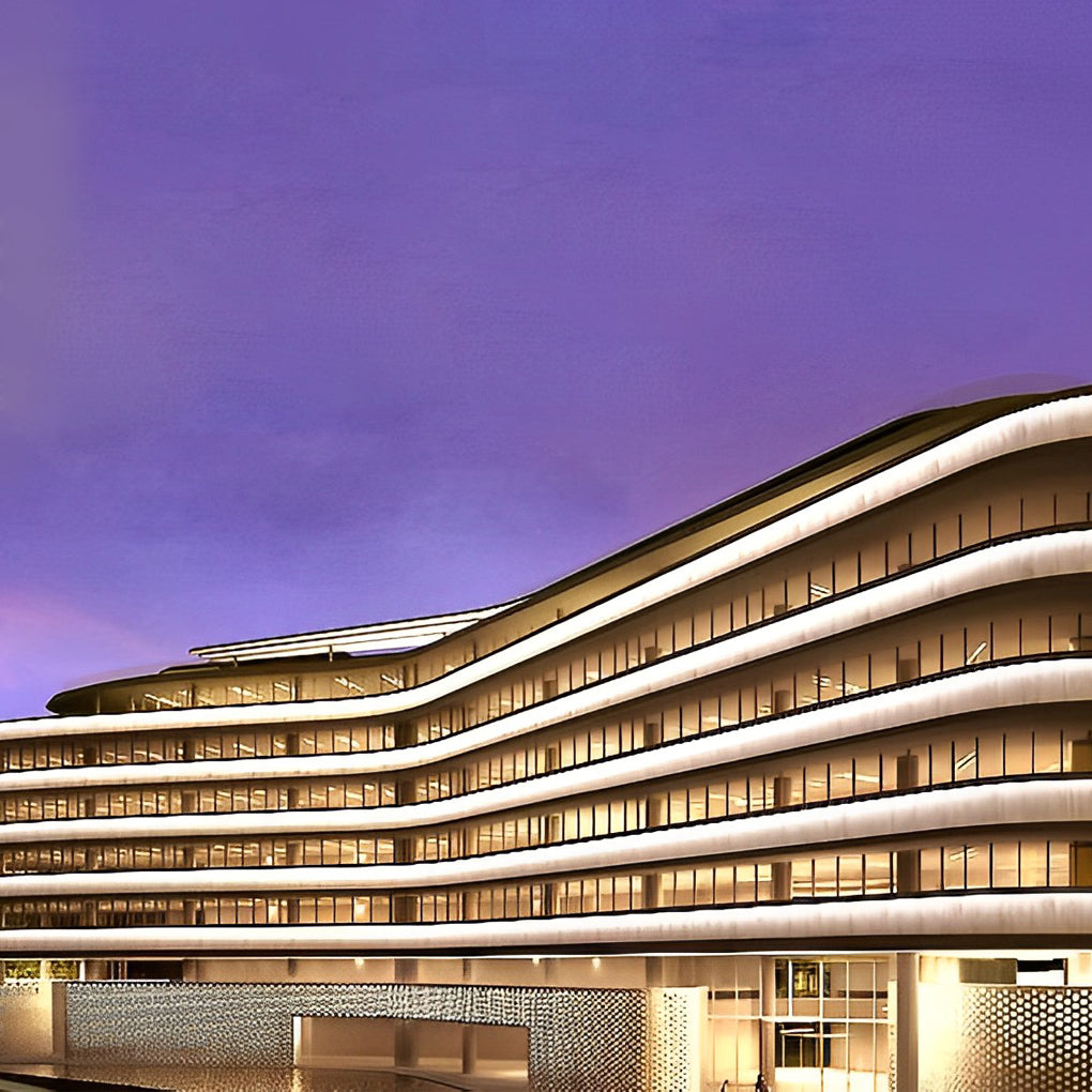 Low voltage wall wash light casting a soft glow on a modern multi-story building during twilight hours.