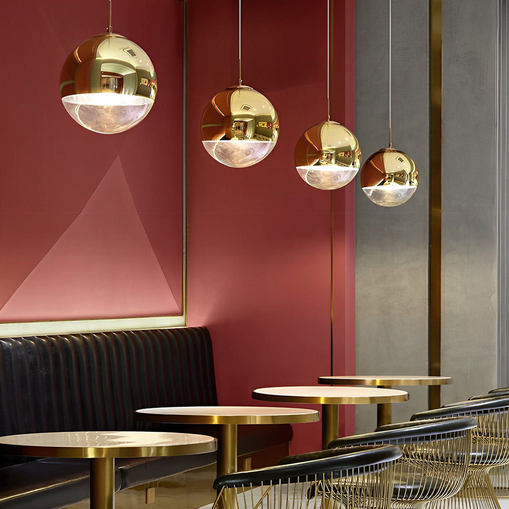 A row of luxury gold sphere pendant lights in a modern restaurant lounge with chic red walls.