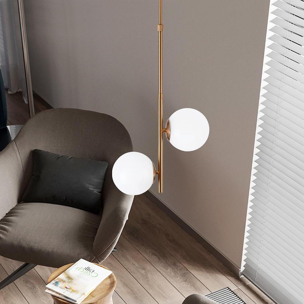 Pair of Vertical Gold Pendant lights illuminating a marble dining table in a white room.