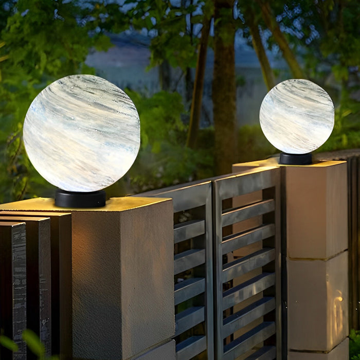 Globe pillar lights with marble texture illuminating modern garden pathway at dusk.