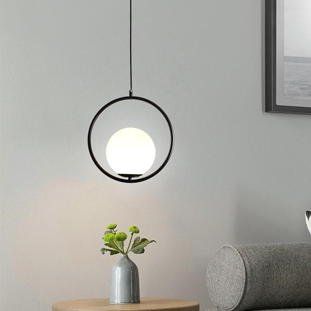 Sleek minimalist black circular pendant light hanging in a bright living room over a table.