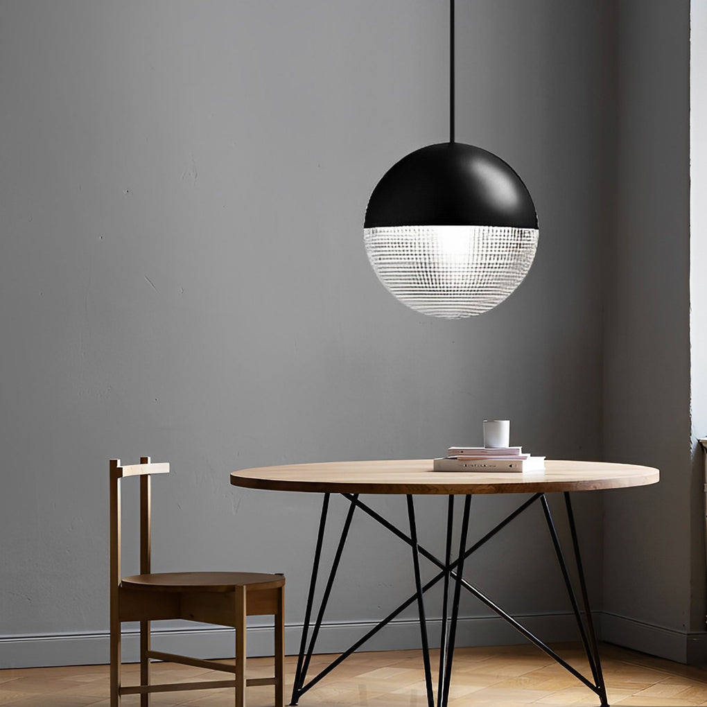 Single black globe pendant light hanging over a round wood table against a minimalist wall.