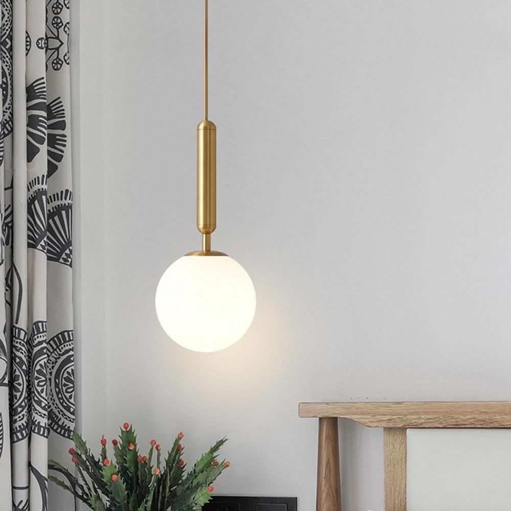 Minimalist gold hanging lights featuring a sleek brass stem and a warm glowing white glass orb.
