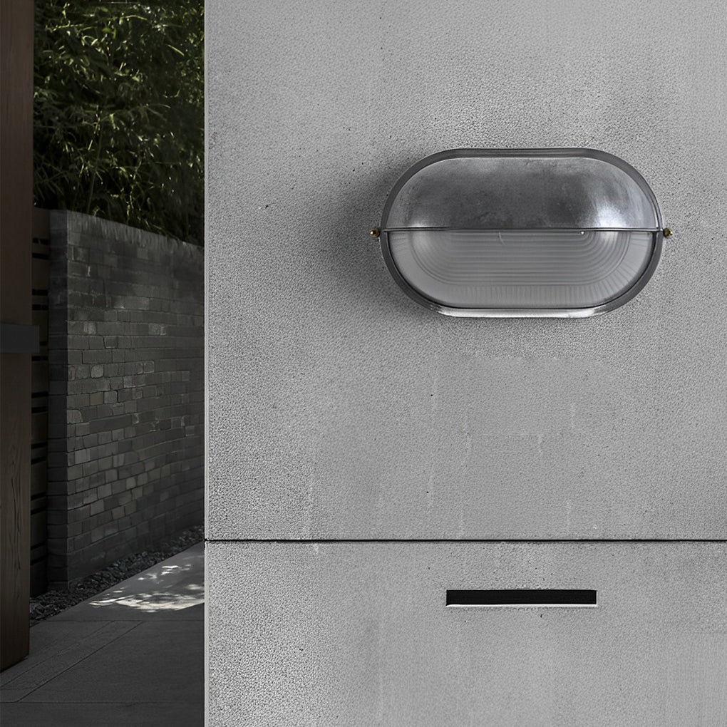 Minimalist oval bulkhead wall light with metal housing mounted on a modern exterior wall.