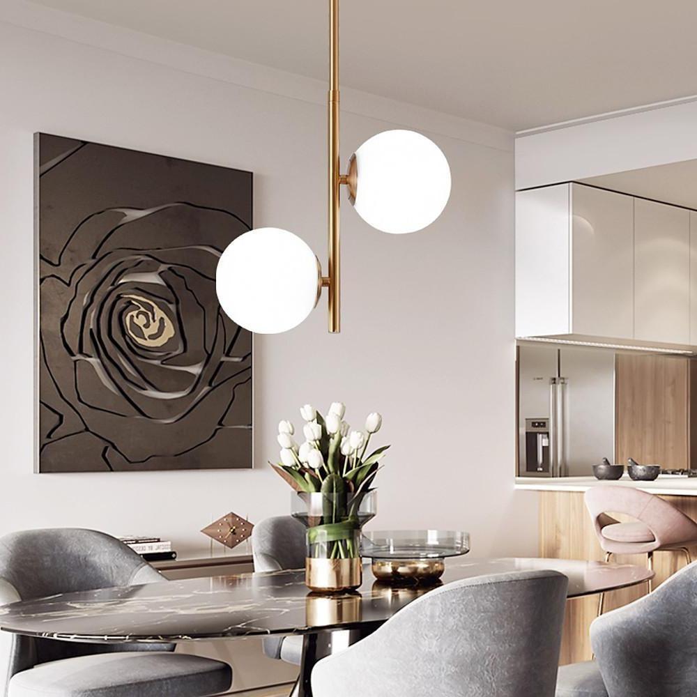 Sleek Vertical Gold Pendant light hanging above a white armchair in a minimalist corner.