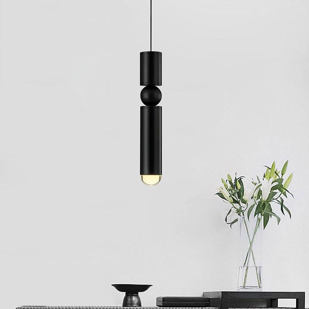 Minimalist single black cylinder pendant light with sphere detail hanging over a dining table.