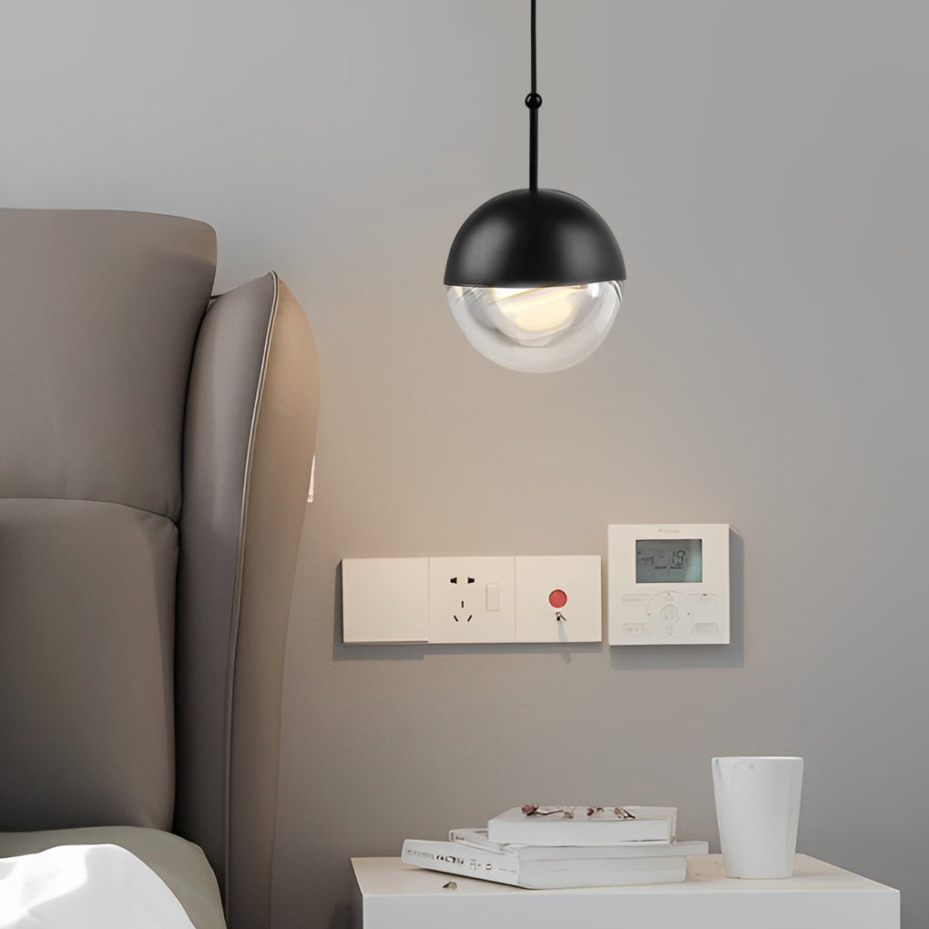 Sleek black globe pendant light bedside lamp in a modern bedroom with a minimalist grey wall.