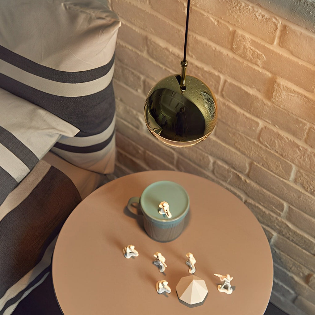 Modern globe pendant light casting a warm glow on a bedside table with a rustic brick wall.