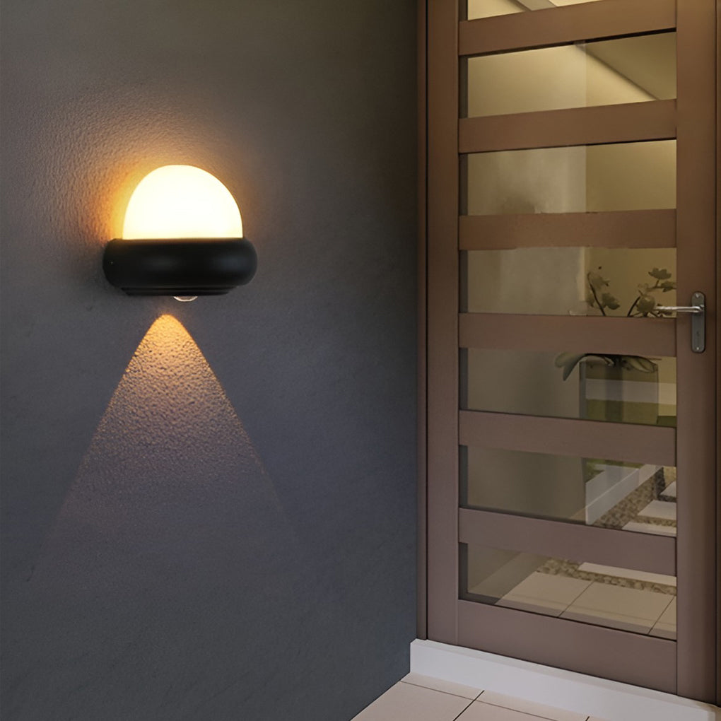Modern globe wall sconce with black finish, adding a touch of sophistication to an outdoor living area.