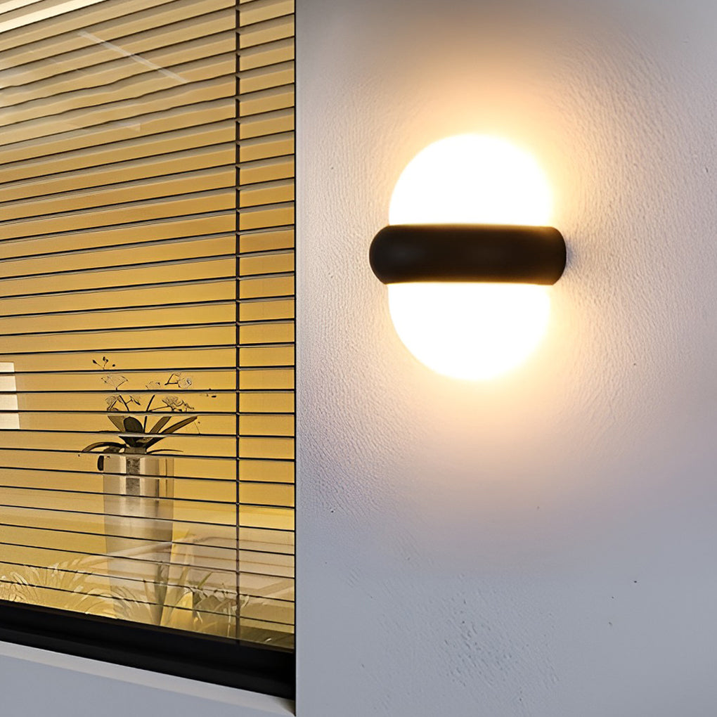 Modern globe wall sconce in black, providing warm light near a wooden fence for cozy ambiance.