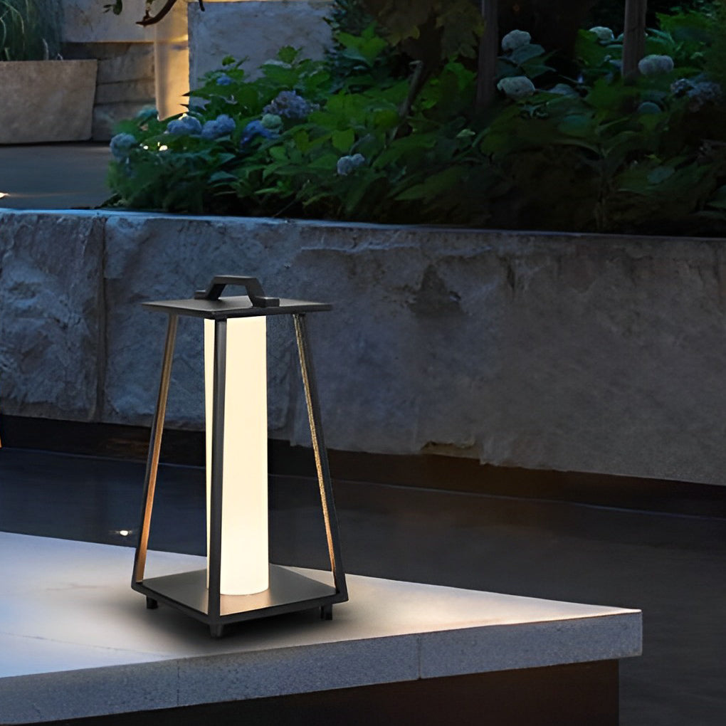 Modern portable outdoor lantern set on a concrete ledge beside lush garden plants.