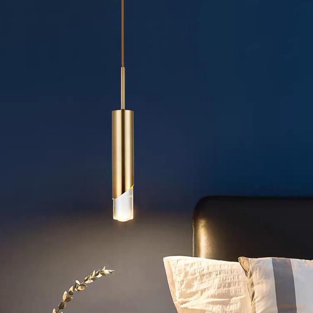Modern Slanted Gold Cylinder Pendant light as a luxury bedside lamp against a deep blue wall.